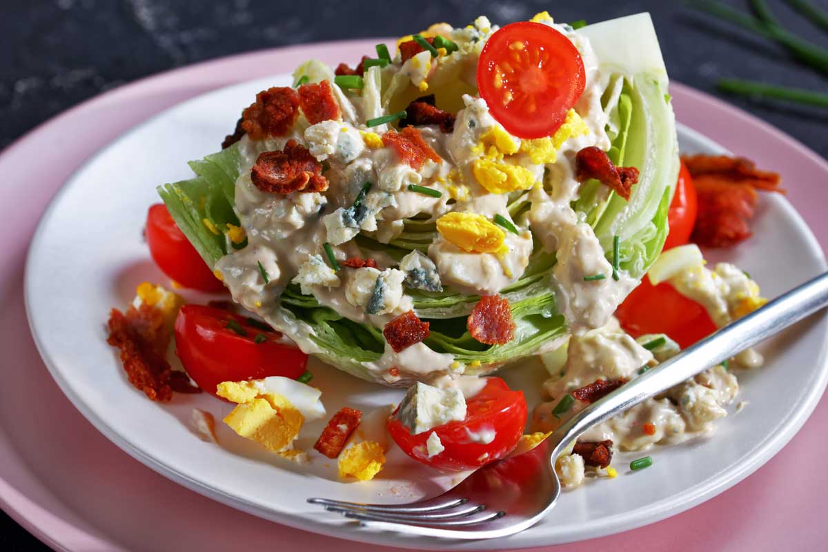 wedge-salad A wedge salad with tomatoes, bacon, crumbled blue cheese and hard boiled egg.