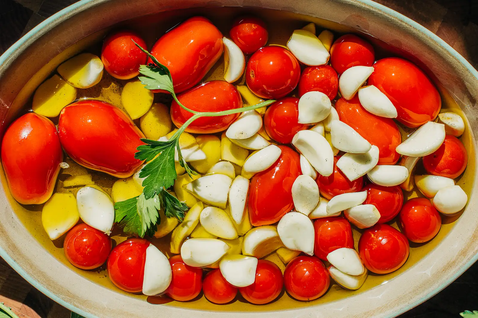 Garlic_Tomato_Confit garlic and tomatoes in a baking dish covered in olive oil
