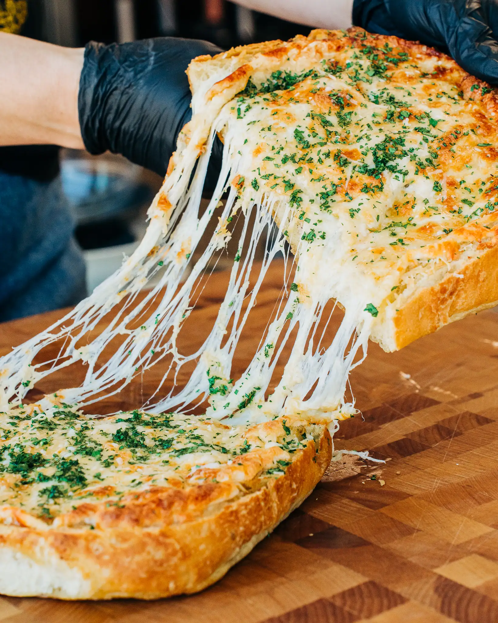 garlic_bread A person pulling a loaf of cheesy garlic bread apart