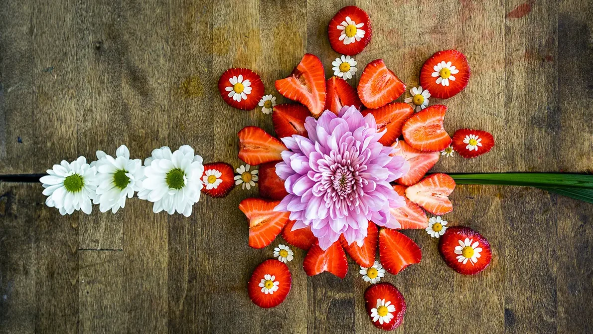 Strawberries sliced and arranged with flowers for a colorful display.