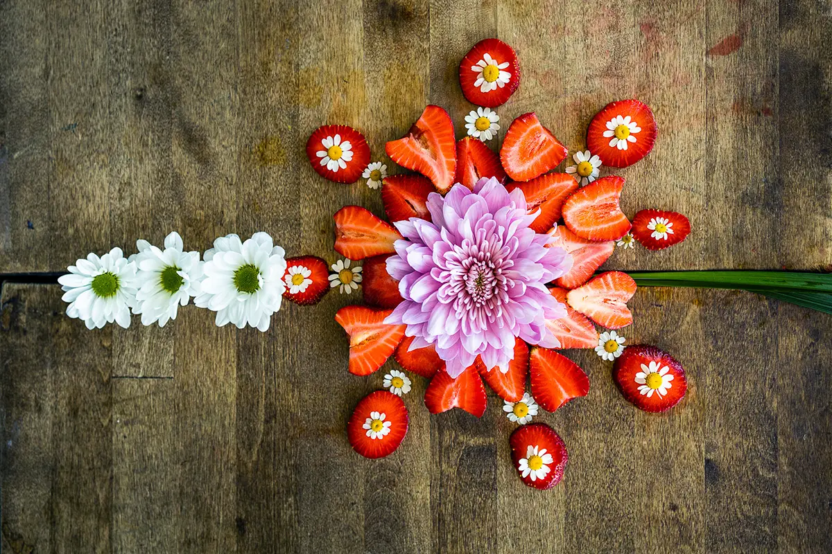 Strawberries sliced and arranged with flowers for a colorful display.